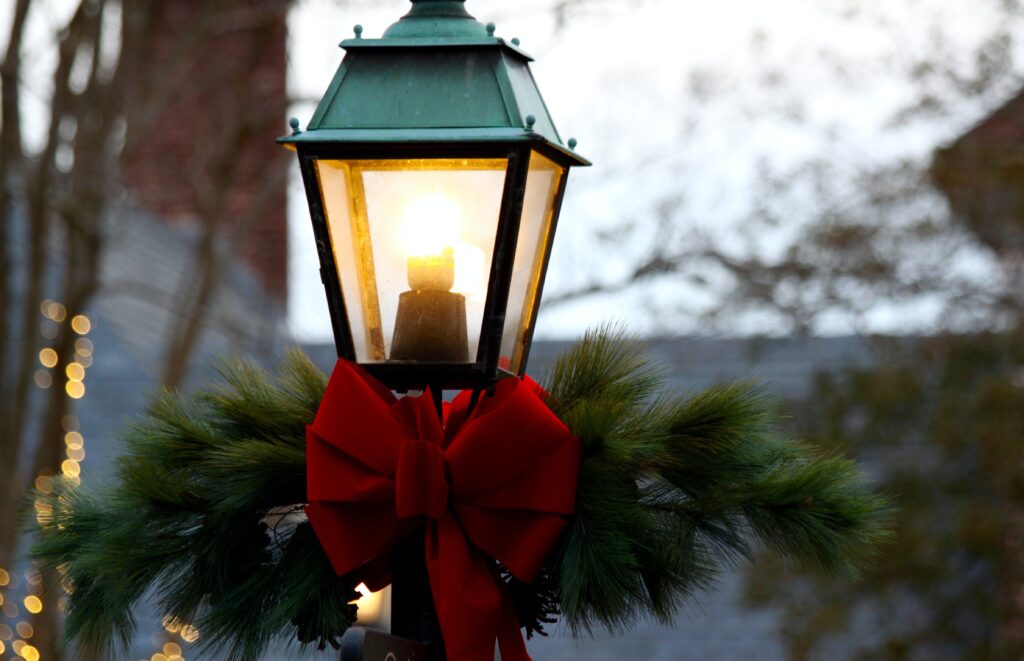 chillly winter sk, lonely birch trees in the backdrop of an old fashioned streetlamp festooned with a red Chritmas bow